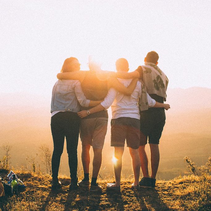 Image of friends hugging over a hill